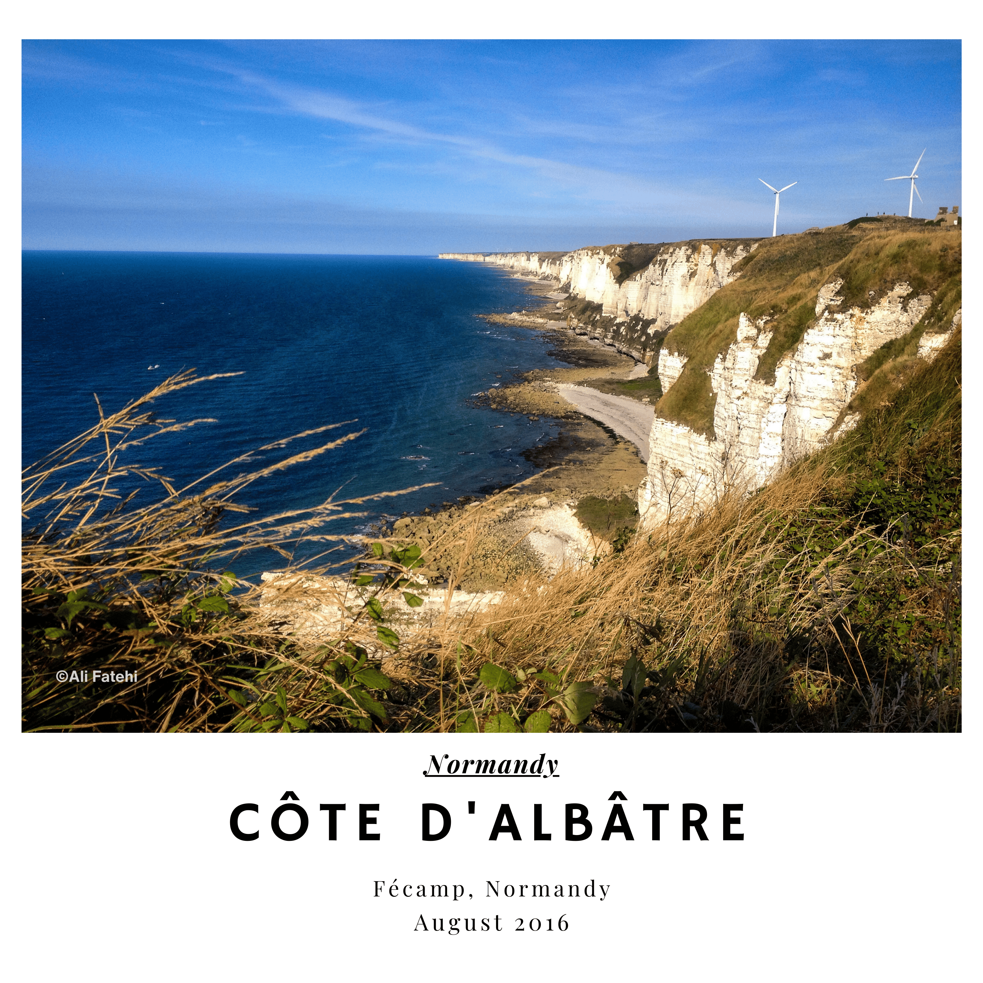 A scenic view of the Côte d'Albâtre cliffs in Fécamp, Normandy, with the ocean, beach, and wind turbines in the background, taken in August 2016.